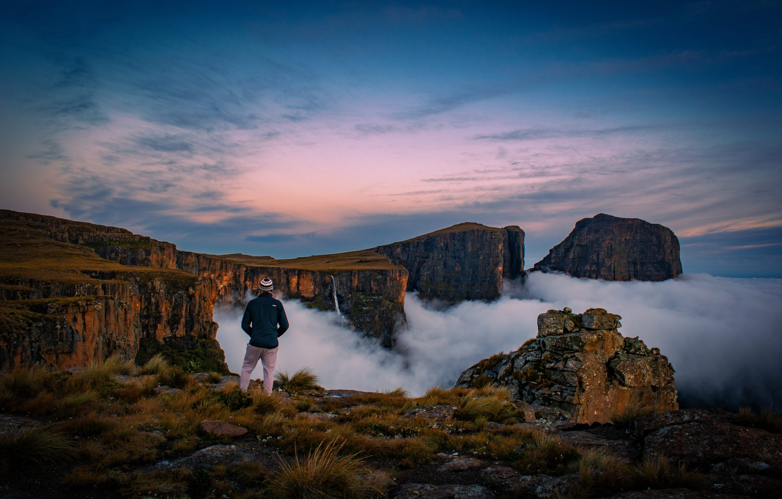 Hiking the Drakensberg Grand Traverse escarpment at sunrise with views of the mountain peaks in South Africa.